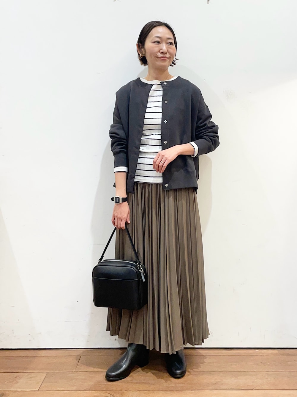 ベージュ系のスカート、ブラック系のショルダーバッグ、グレー系のカーディガン/ボレロを着用したレディースの冬コーディネートの2枚目の写真