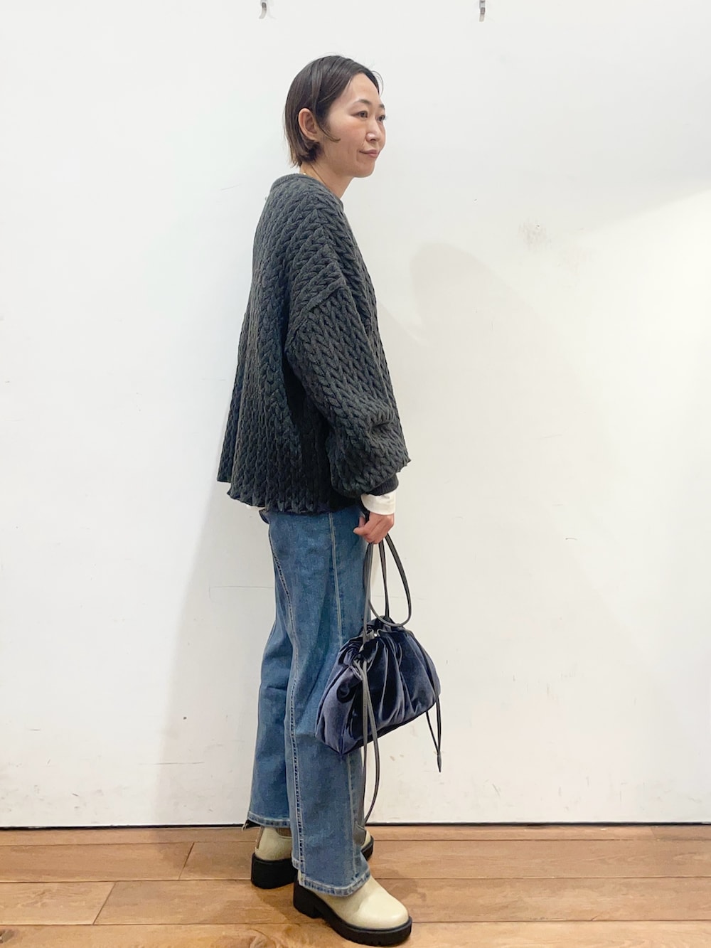 グレー系のニット/セーター、ホワイト系のTシャツ/カットソー、ブルー系のショルダーバッグを着用したレディースの冬コーディネートの4枚目の写真