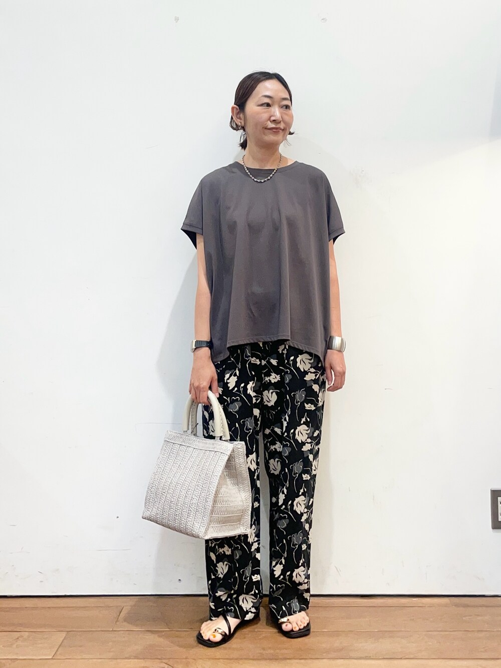 グレー系のTシャツ/カットソー、グレー系のハンドバッグ、ブラック系のサンダルを着用したレディースの夏コーディネートの2枚目の写真