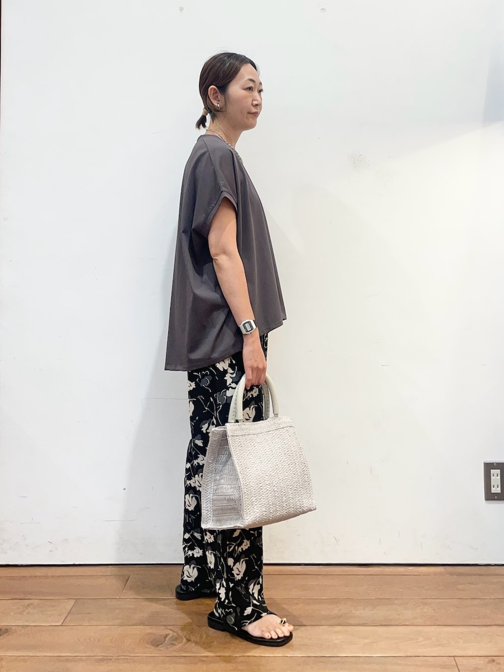 グレー系のTシャツ/カットソー、グレー系のハンドバッグ、ブラック系のサンダルを着用したレディースの夏コーディネートの4枚目の写真