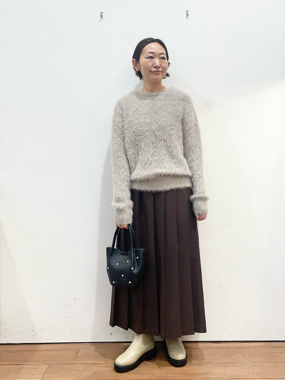 グレー系のニット/セーター、ベージュ系のブーツ、ブラウン系のスカートを着用したレディースの冬コーディネートの2枚目の写真