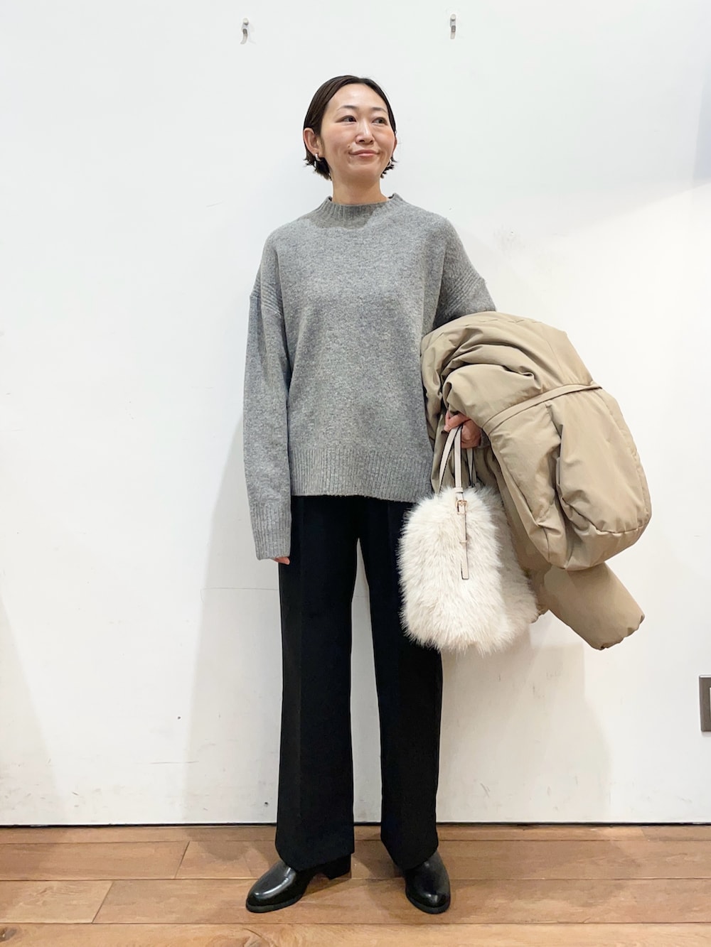 ブラウン系のダウンジャケット/コート、グレー系のニット/セーター、ブラック系のブーツを着用したレディースの冬コーディネートの6枚目の写真