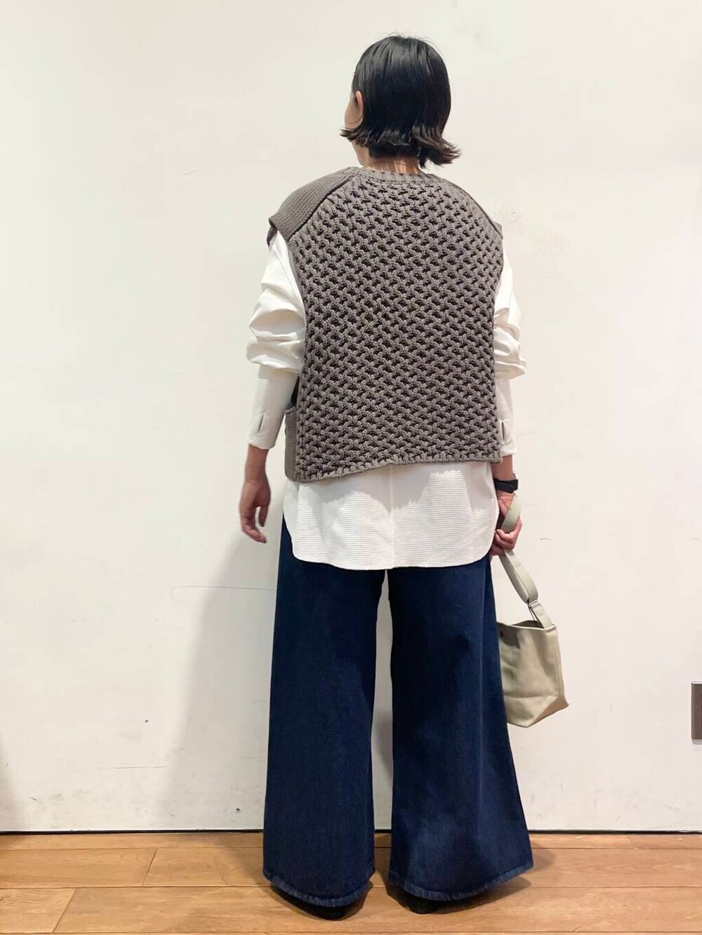 ブラック系のバレエシューズ、ブルー系のデニムパンツ、グレー系のベストを着用したレディースの秋コーディネートの6枚目の写真