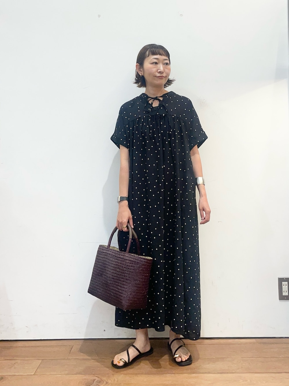 ブラック系のワンピース、ブラック系のサンダル、ブラウン系のトートバッグを着用したレディースの夏コーディネートの3枚目の写真