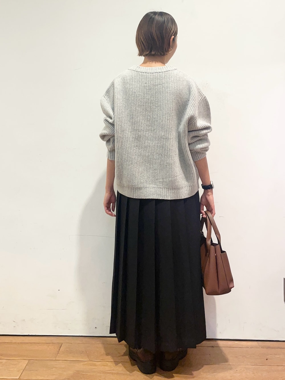 ブラック系のスカート、ブラウン系のトートバッグ、ブラウン系のブーツを着用したレディースの秋コーディネートの5枚目の写真