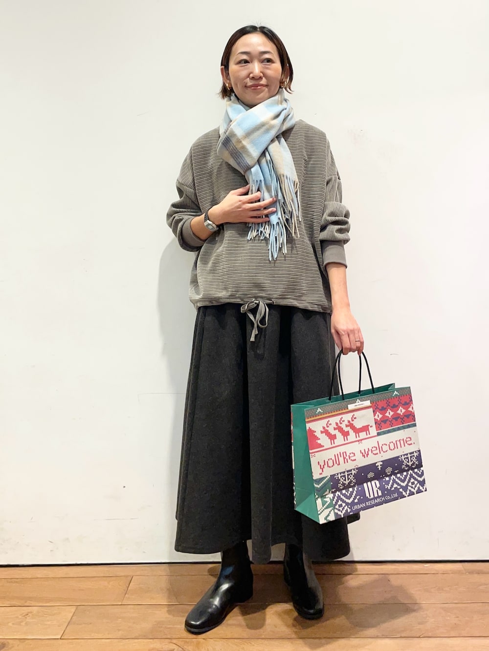 グレー系のスカート、ブラック系のブーツ、グレー系のTシャツ/カットソーを着用したレディースの冬コーディネートの2枚目の写真