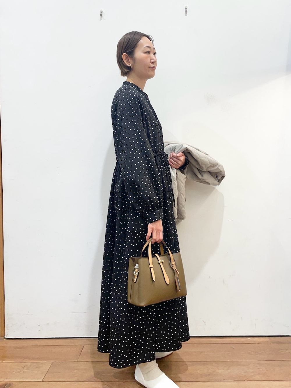 グレー系のダウンジャケット/コート、ホワイト系のその他シューズ、ブラック系のワンピースを着用したレディースの春コーディネートの7枚目の写真