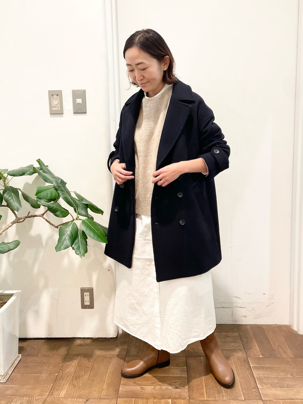 ベージュ系のニット/セーター、ホワイト系のワンピース、ブラウン系のブーツを着用したレディースの冬コーディネートの2枚目の写真