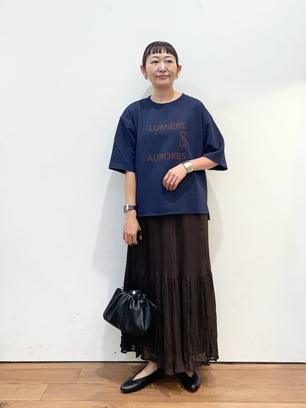 ブルー系のTシャツ/カットソー、ブラウン系のスカート、ブラック系のショルダーバッグを着用したレディースの秋コーディネートの2枚目の写真