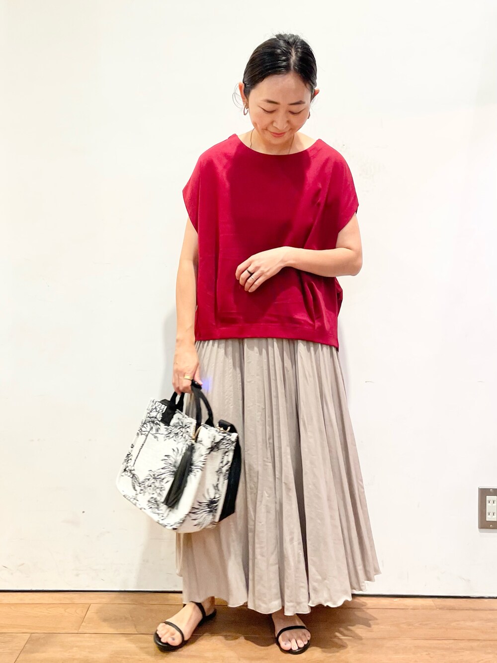 レッド系のTシャツ/カットソー、ベージュ系のスカート、ブラック系のサンダルを着用したレディースの夏コーディネートの3枚目の写真