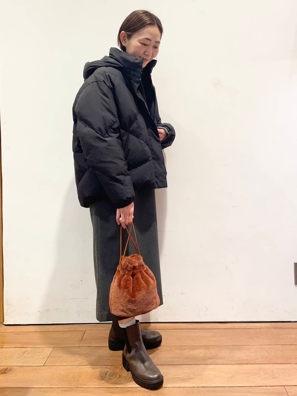 ブラック系のダウンジャケット/コート、グレー系のワンピース、ブラウン系のブーツを着用したレディースの冬コーディネートの3枚目の写真