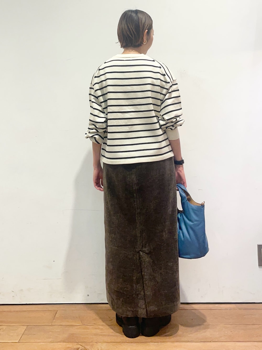 ホワイト系のカーディガン/ボレロ、ブラウン系のスカート、ブラック系のブーツを着用したレディースの秋コーディネートの5枚目の写真