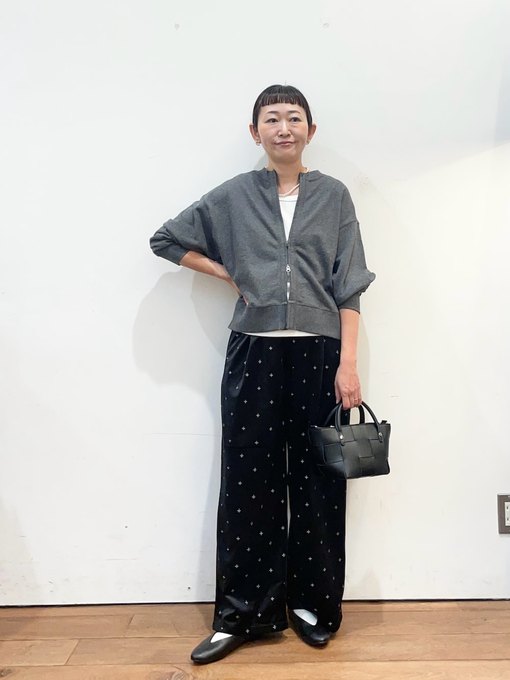 グレー系のカーディガン/ボレロ、ホワイト系のタンクトップ、ブラック系のパンプスを着用したレディースの秋コーディネートの2枚目の写真
