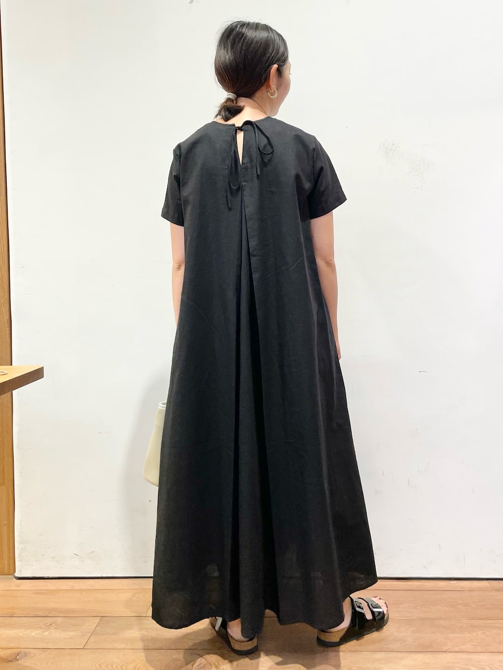 ブラック系のワンピース、ベージュ系のショルダーバッグ、ブラック系のサンダルを着用したレディースの夏コーディネートの3枚目の写真