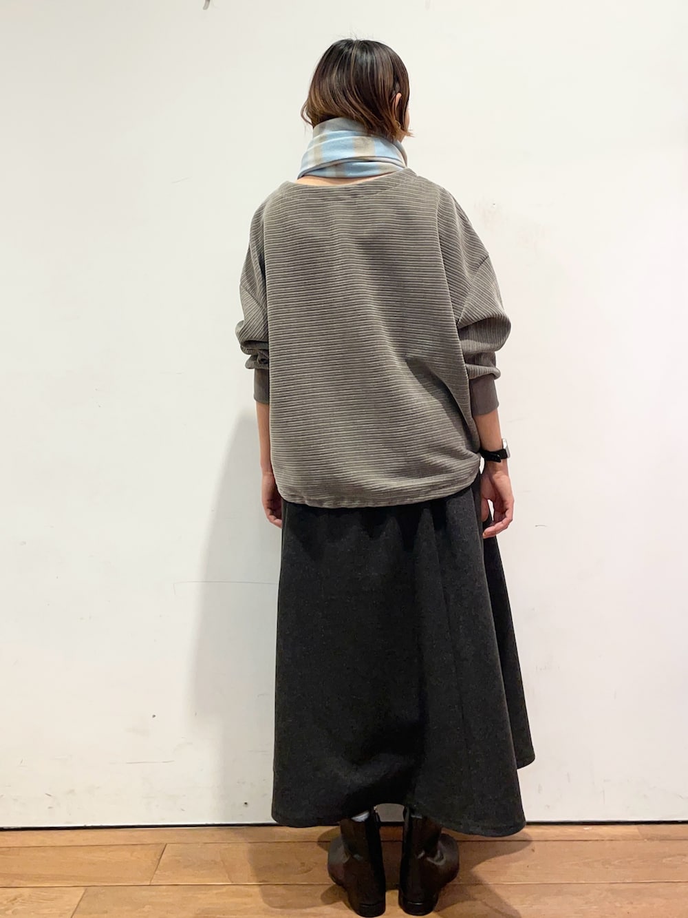 グレー系のスカート、ブラック系のブーツ、グレー系のTシャツ/カットソーを着用したレディースの冬コーディネートの5枚目の写真