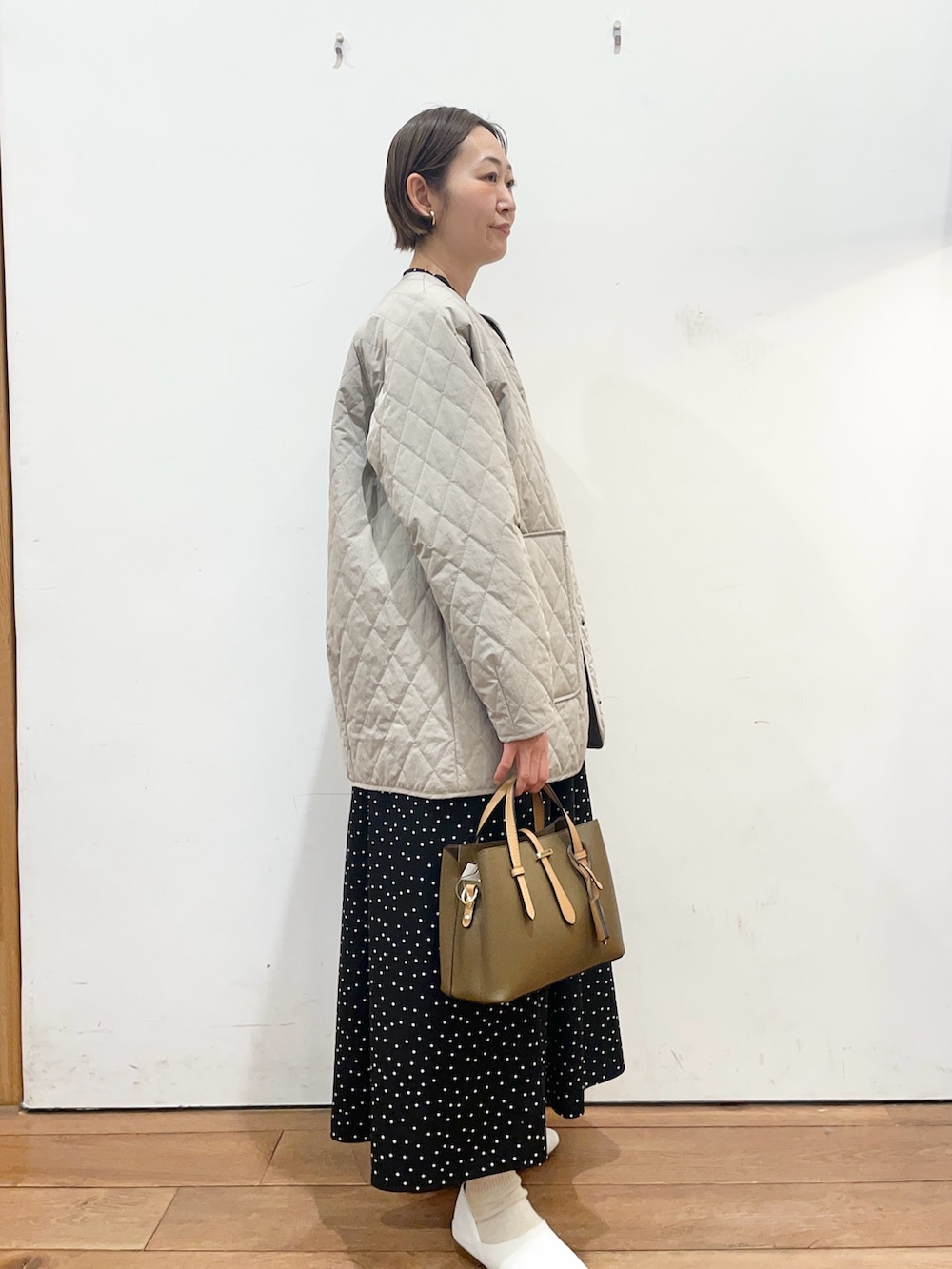グレー系のダウンジャケット/コート、ホワイト系のその他シューズ、ブラック系のワンピースを着用したレディースの春コーディネートの3枚目の写真