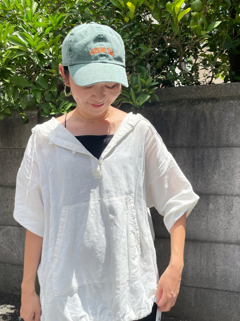 ブラック系のサンダル、ホワイト系のパーカー、グリーン系のキャップを着用したレディースの夏コーディネートの5枚目の写真