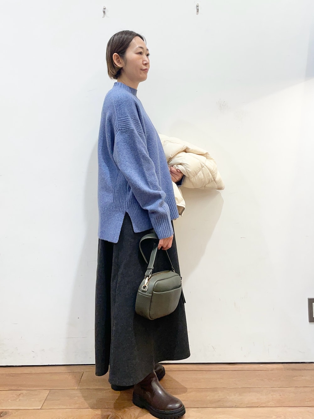 ホワイト系のダウンジャケット/コート、ブルー系のニット/セーター、グリーン系のショルダーバッグを着用したレディースの冬コーディネートの7枚目の写真