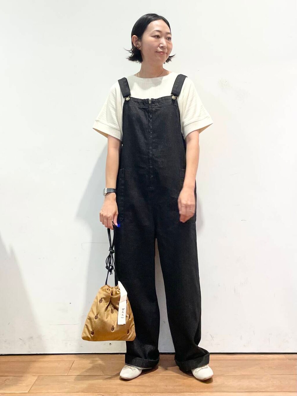 ホワイト系のTシャツ/カットソー、ブラウン系のバレエシューズ、ブラック系のサロペット/オーバーオールを着用したレディースの秋コーディネートの4枚目の写真