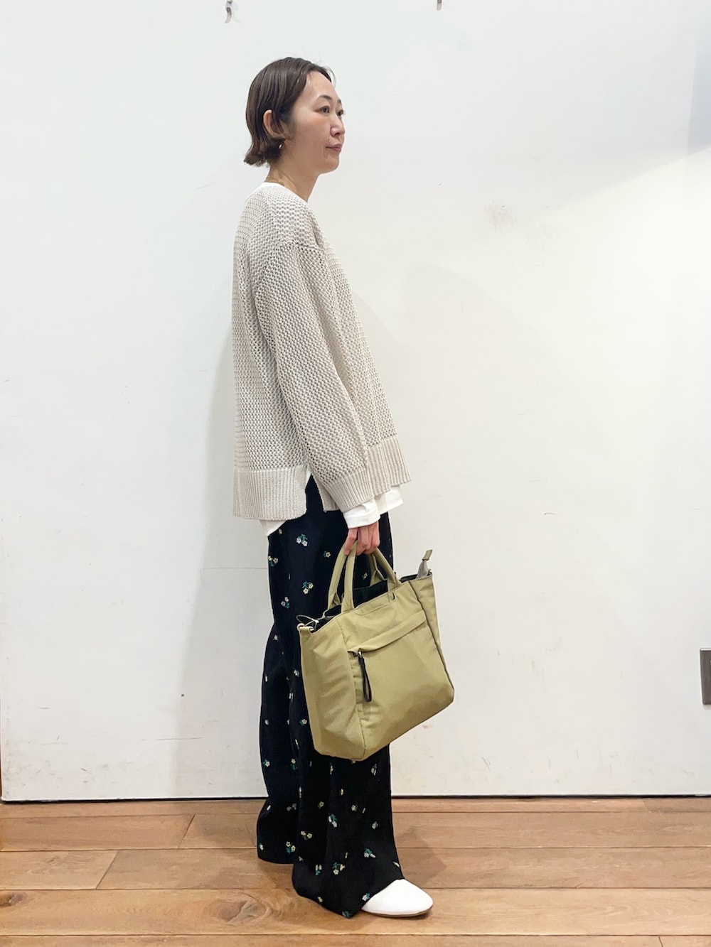グレー系のニット/セーター、ホワイト系のTシャツ/カットソー、ベージュ系のトートバッグを着用したレディースの春コーディネートの3枚目の写真
