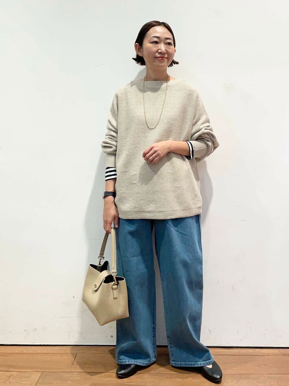 ブラック系のパンプス、ベージュ系のニット/セーター、ベージュ系のショルダーバッグを着用したレディースの秋コーディネートの2枚目の写真