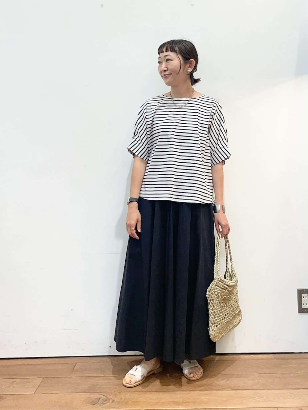 ホワイト系のTシャツ/カットソー、ブラック系のスカート、ホワイト系のサンダルを着用したレディースの夏コーディネートの2枚目の写真