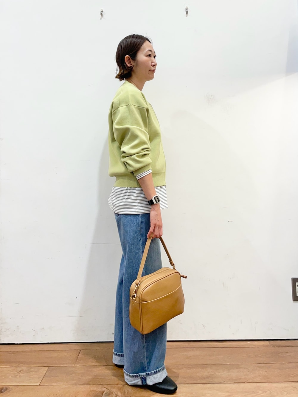 グリーン系のカーディガン/ボレロ、ホワイト系のTシャツ/カットソー、ブルー系のデニムパンツを着用したレディースの冬コーディネートの3枚目の写真