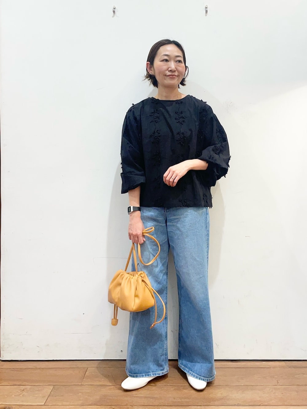 ブラック系のシャツ/ブラウス、ブルー系のデニムパンツ、オレンジ系のショルダーバッグを着用したレディースの冬コーディネートの3枚目の写真