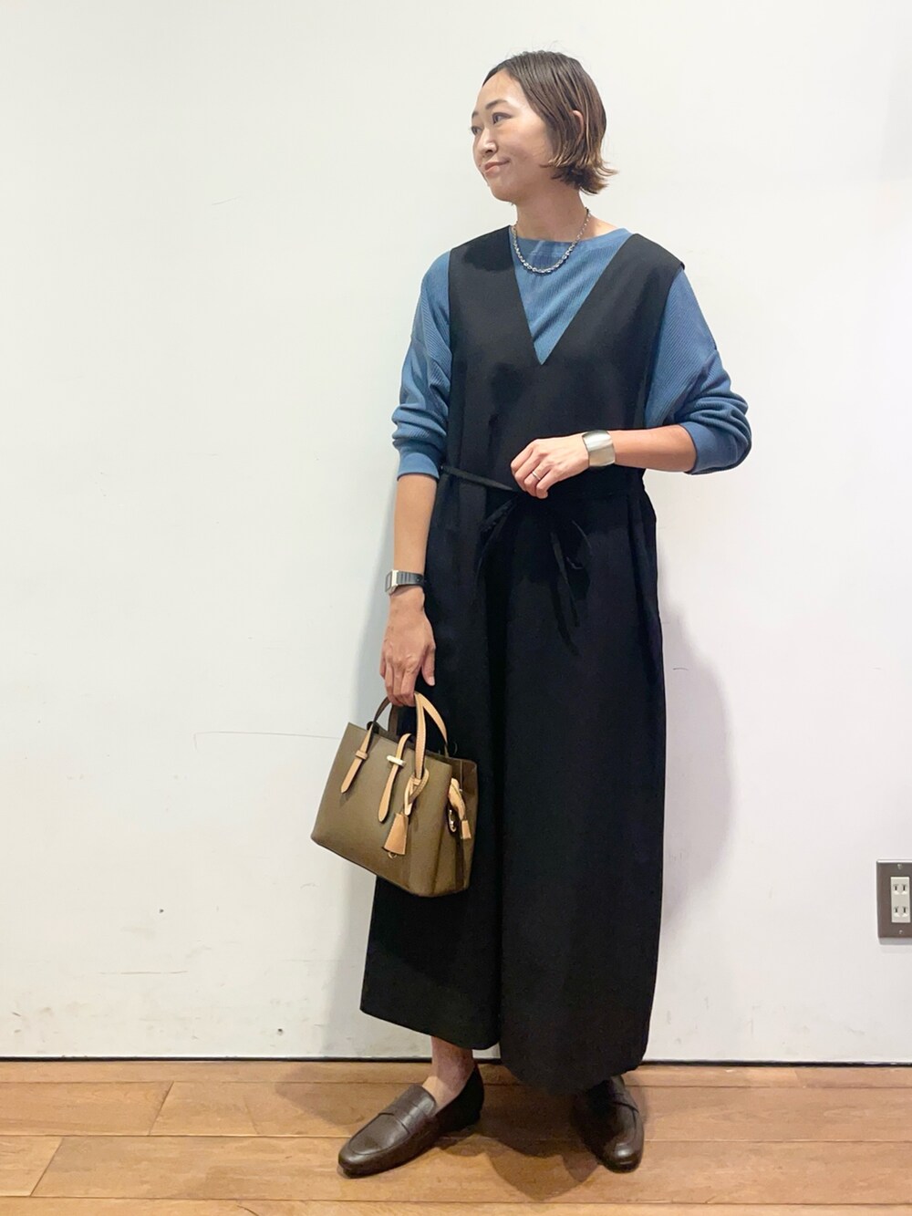 ブラック系のワンピース、ブルー系のTシャツ/カットソー、ブラウン系のパンプスを着用したレディースの秋コーディネートの3枚目の写真