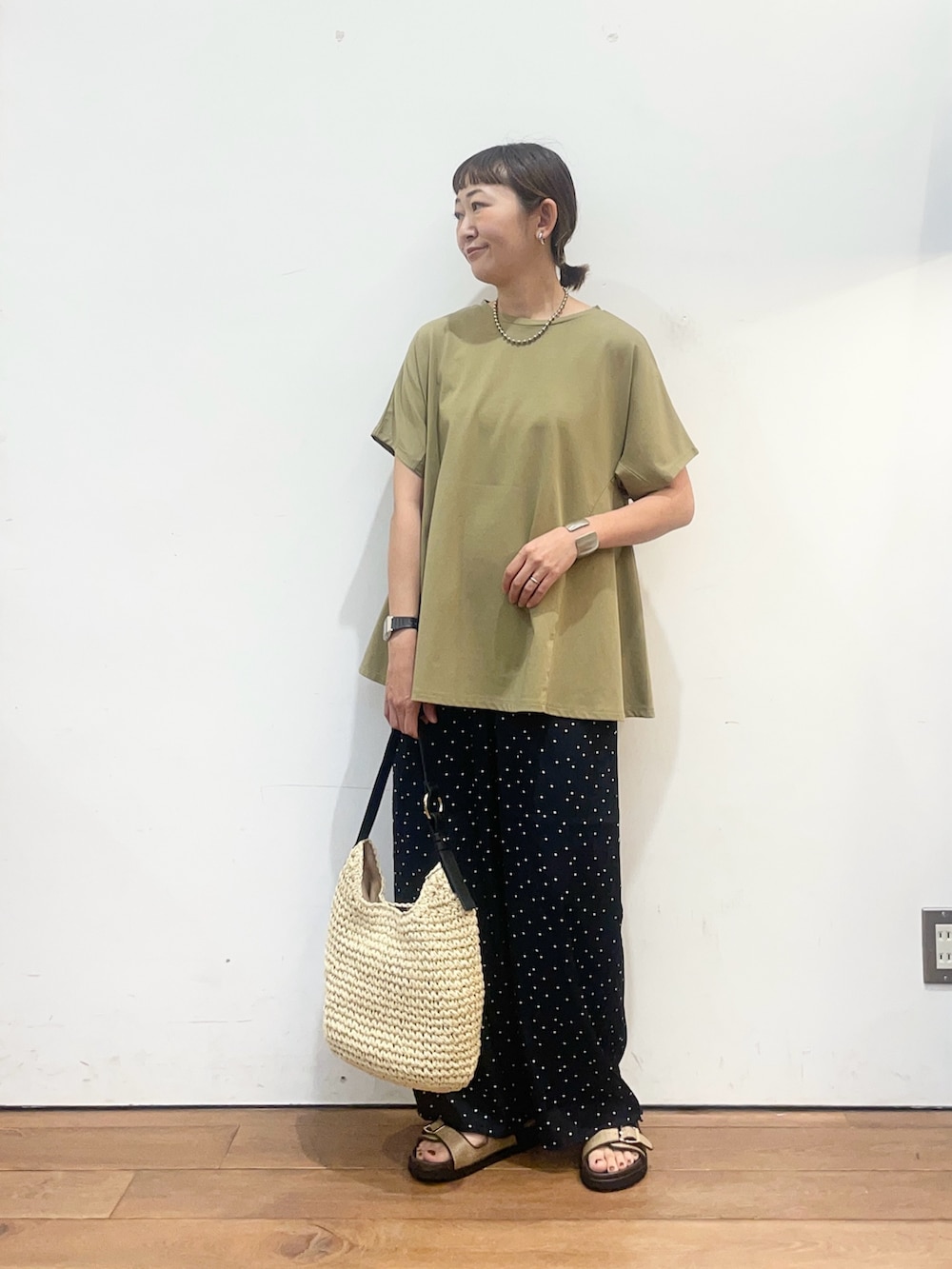 グリーン系のTシャツ/カットソー、ベージュ系のトートバッグ、ベージュ系のサンダルを着用したレディースの夏コーディネートの2枚目の写真