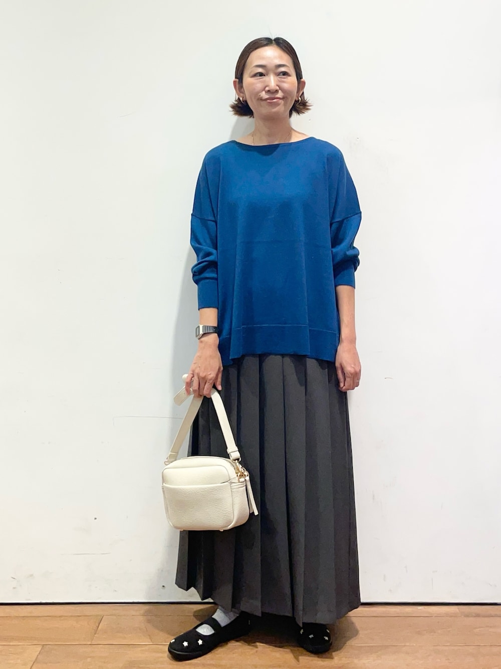 ブルー系のニット/セーター、ブラック系のスニーカー、グレー系のスカートを着用したレディースの秋コーディネートの3枚目の写真