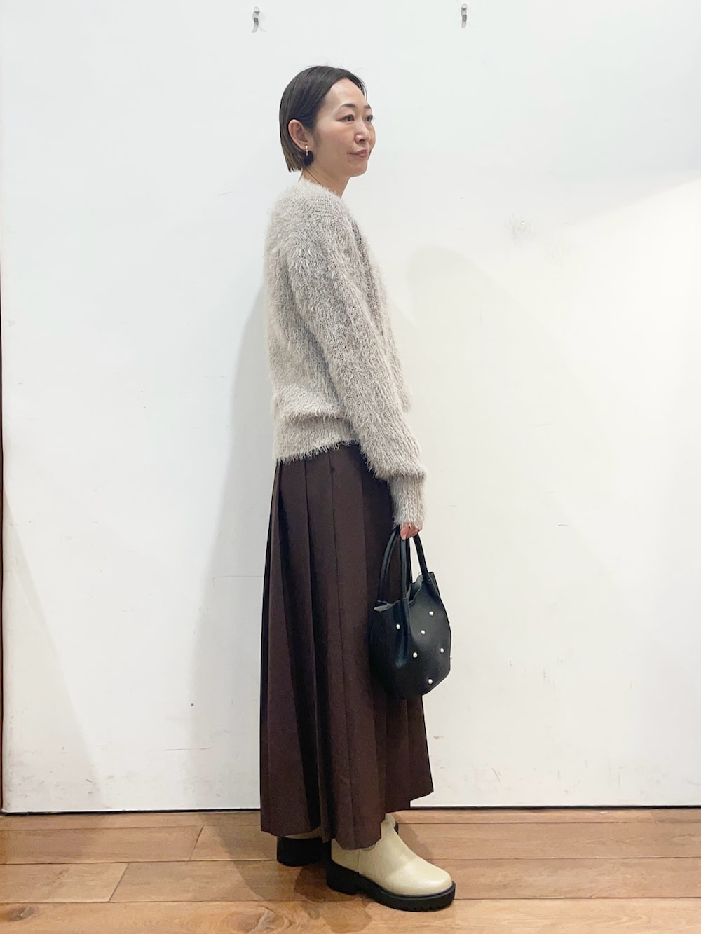 グレー系のニット/セーター、ベージュ系のブーツ、ブラウン系のスカートを着用したレディースの冬コーディネートの3枚目の写真