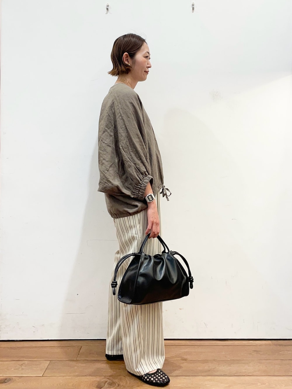 ブラウン系のシャツ/ブラウス、ベージュ系のその他パンツ、ブラック系のトートバッグを着用したレディースの春コーディネートの3枚目の写真