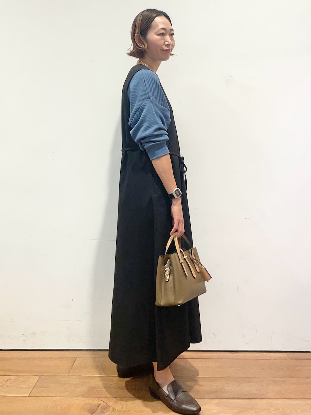 ブラック系のワンピース、ブルー系のTシャツ/カットソー、ブラウン系のパンプスを着用したレディースの秋コーディネートの5枚目の写真