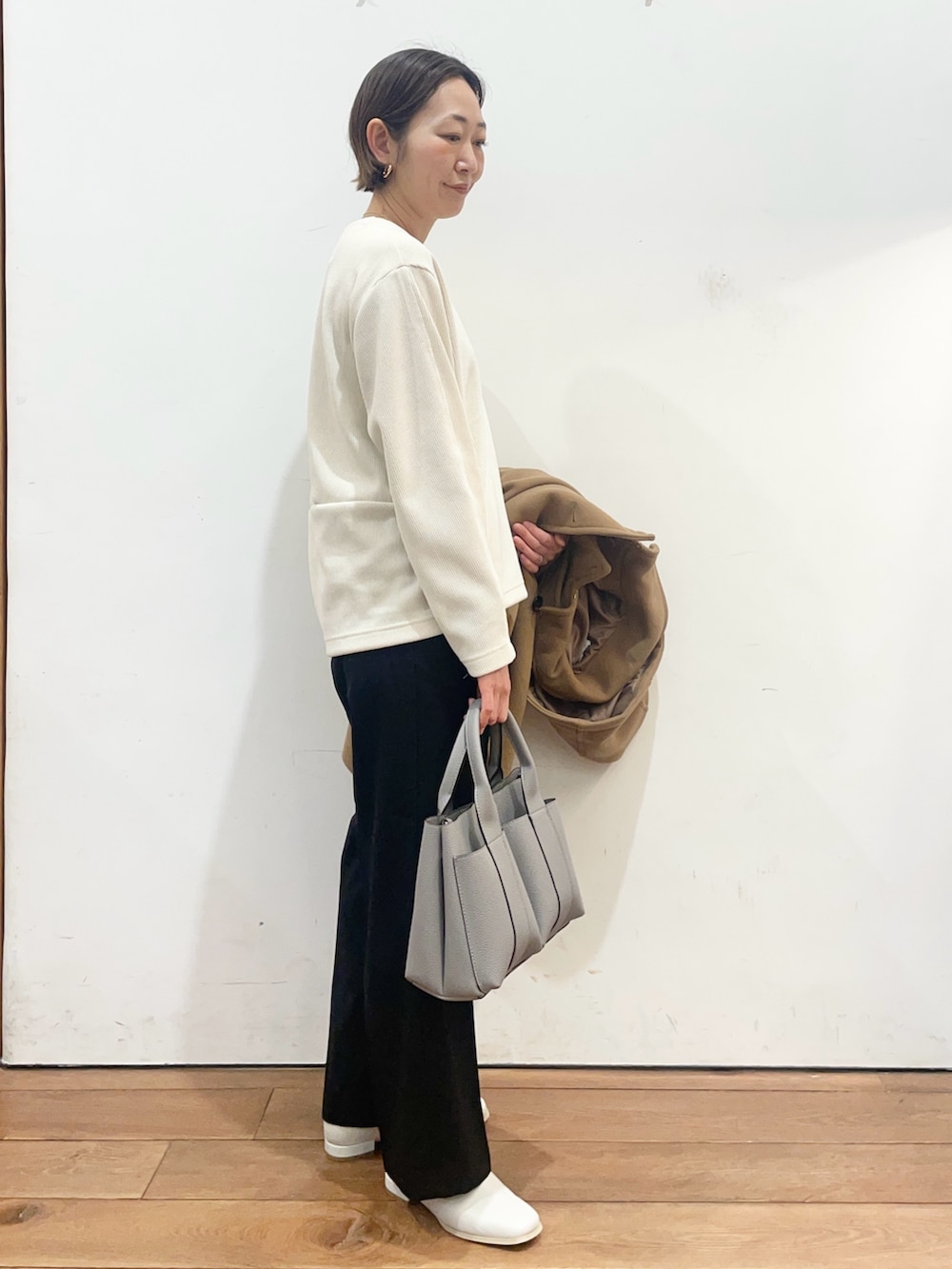 グレー系のトートバッグ、ホワイト系のブーツ、イエロー系のその他アウターを着用したレディースの冬コーディネートの6枚目の写真