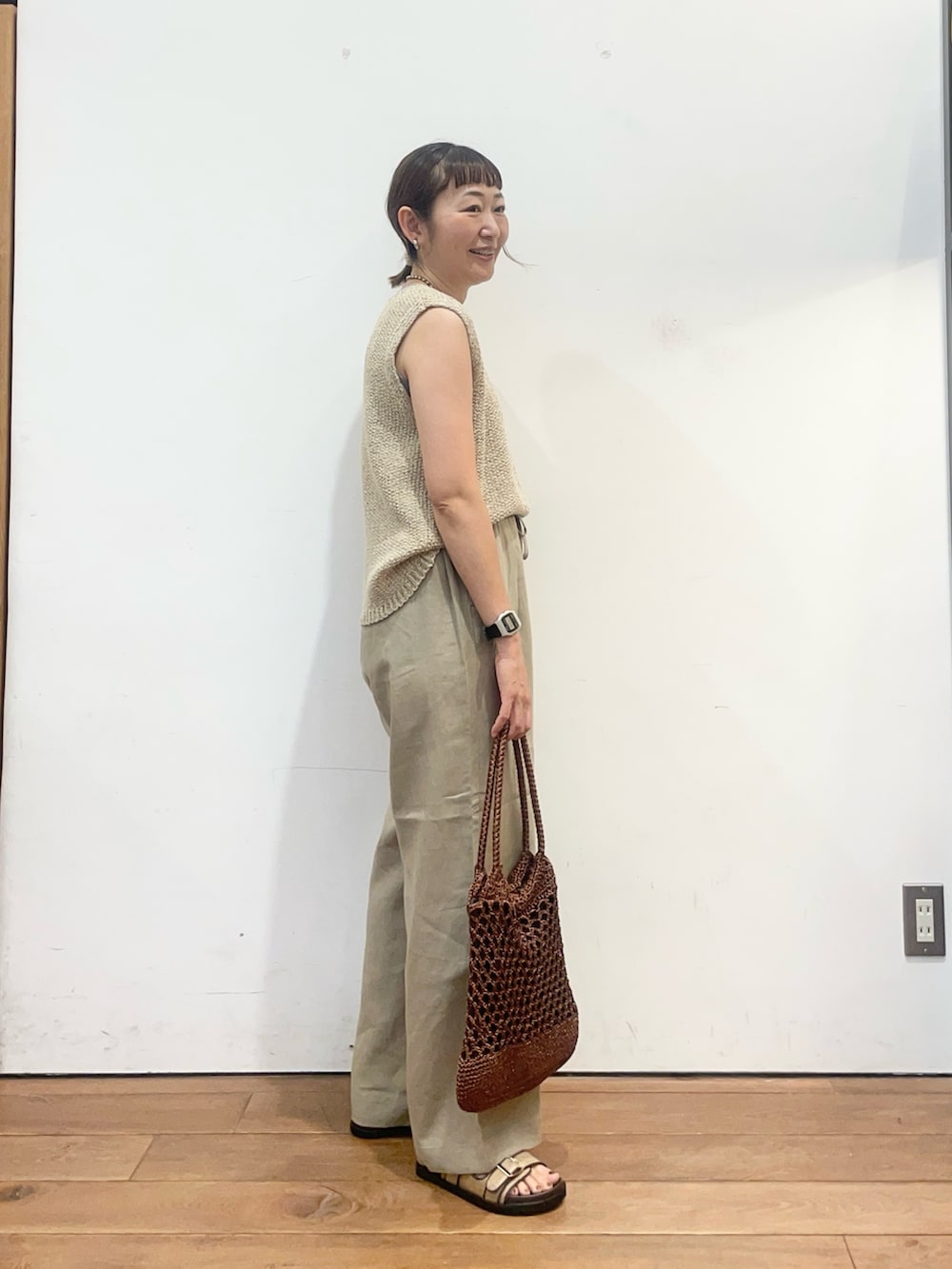 ベージュ系のニット/セーター、ベージュ系のサンダル、ブラウン系のトートバッグを着用したレディースの夏コーディネートの3枚目の写真