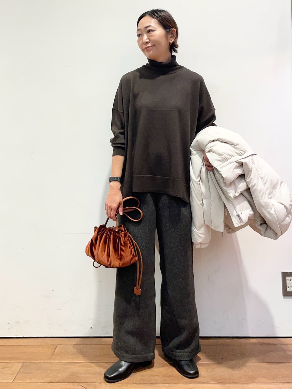 ホワイト系のダウンジャケット/コート、ブラウン系のニット/セーター、ブラック系のブーツを着用したレディースの秋コーディネートの5枚目の写真