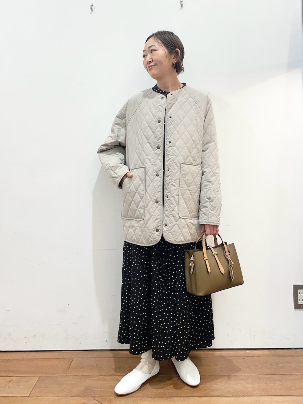 グレー系のダウンジャケット/コート、ホワイト系のその他シューズ、ブラック系のワンピースを着用したレディースの春コーディネートの2枚目の写真