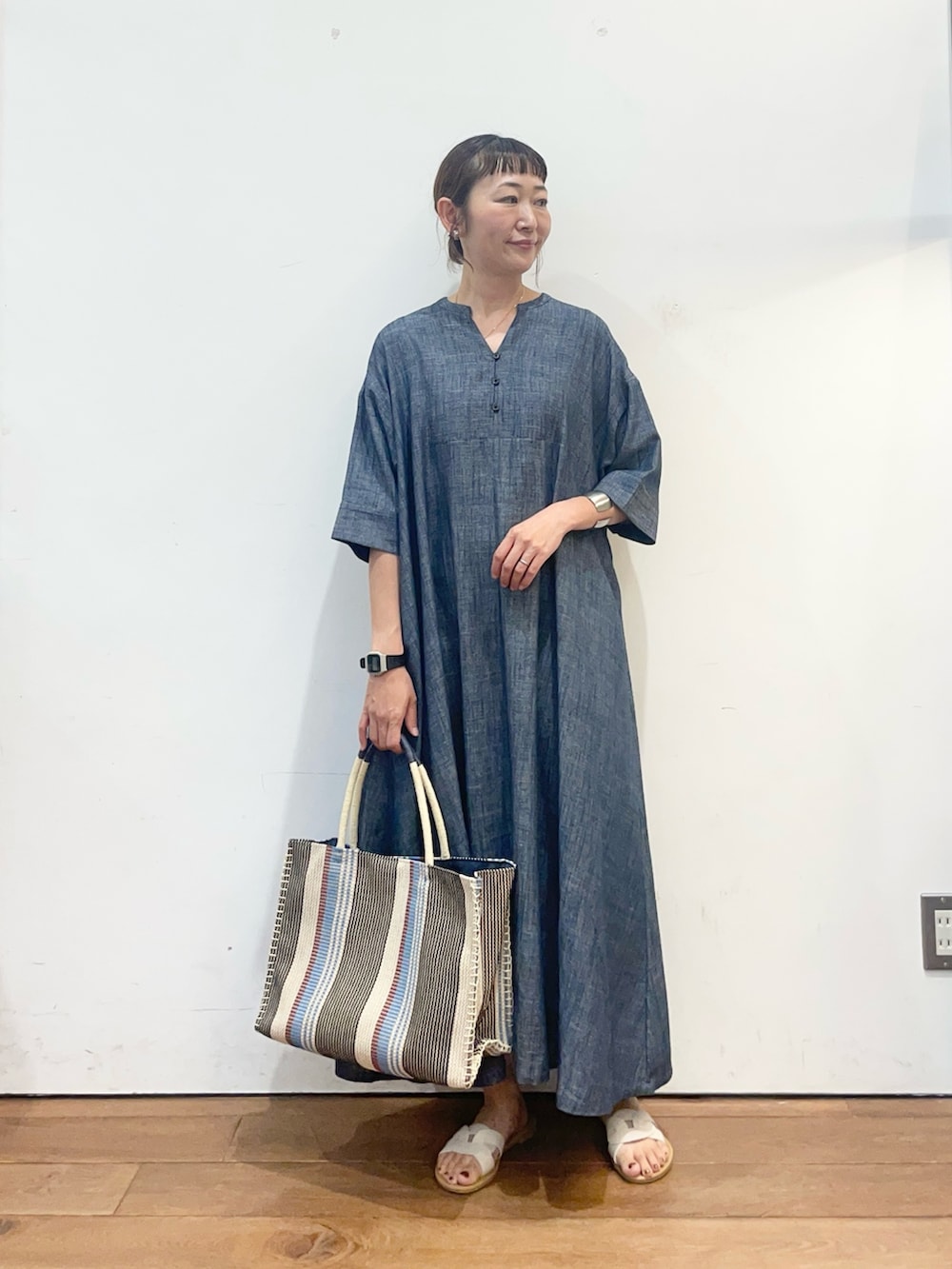 ブルー系のワンピース、ブルー系のトートバッグ、ホワイト系のサンダルを着用したレディースの夏コーディネートの2枚目の写真