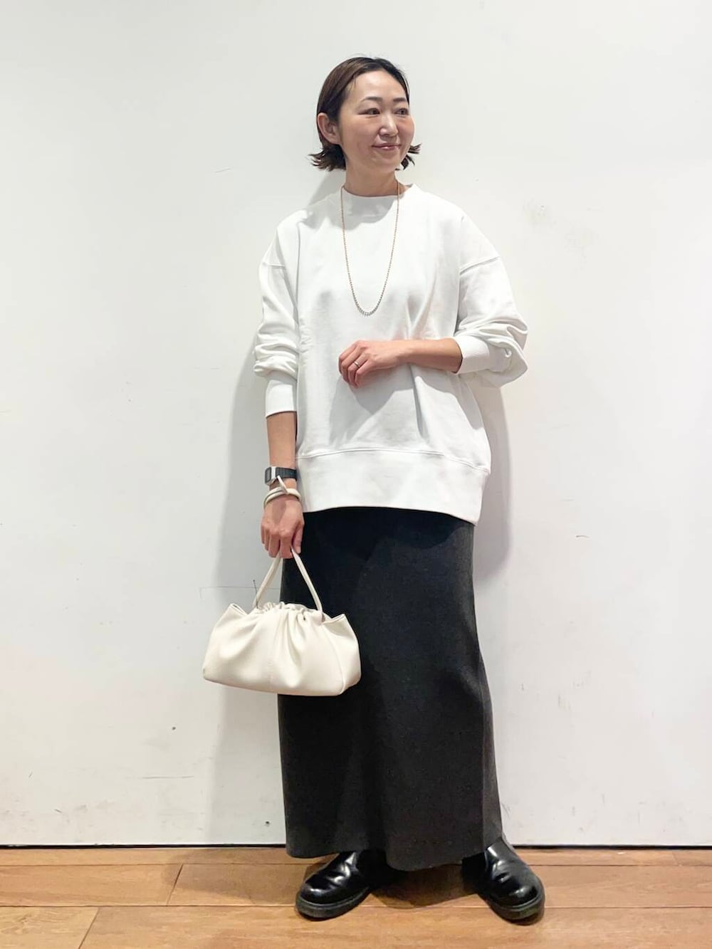 グレー系のスカート、ホワイト系のショルダーバッグ、ホワイト系のTシャツ/カットソーを着用したレディースの冬コーディネートの2枚目の写真