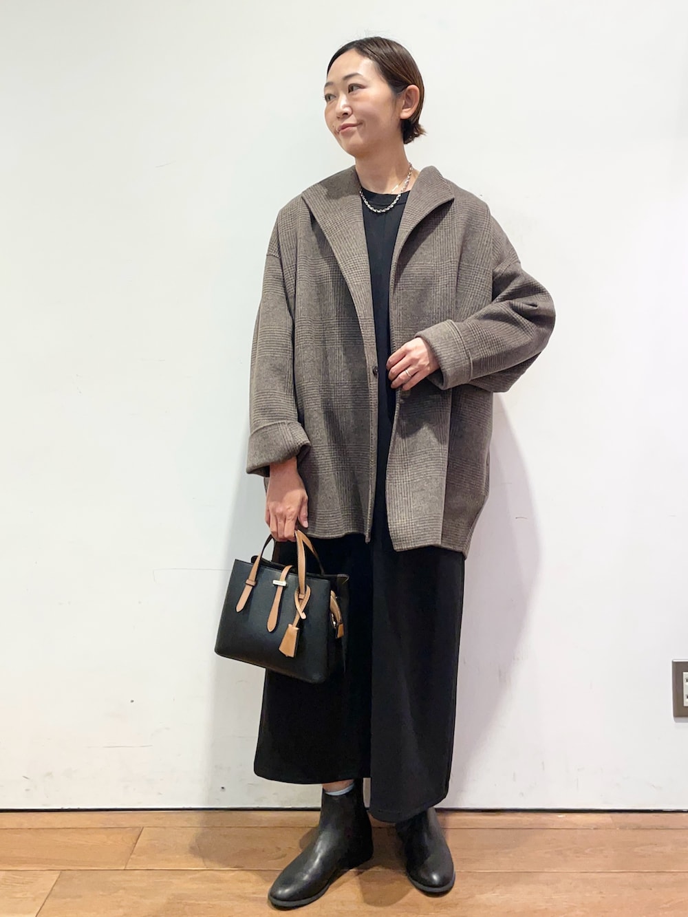 ブラック系のブーツ、ブラック系のハンドバッグ、その他のその他アウターを着用したレディースの秋コーディネートの2枚目の写真