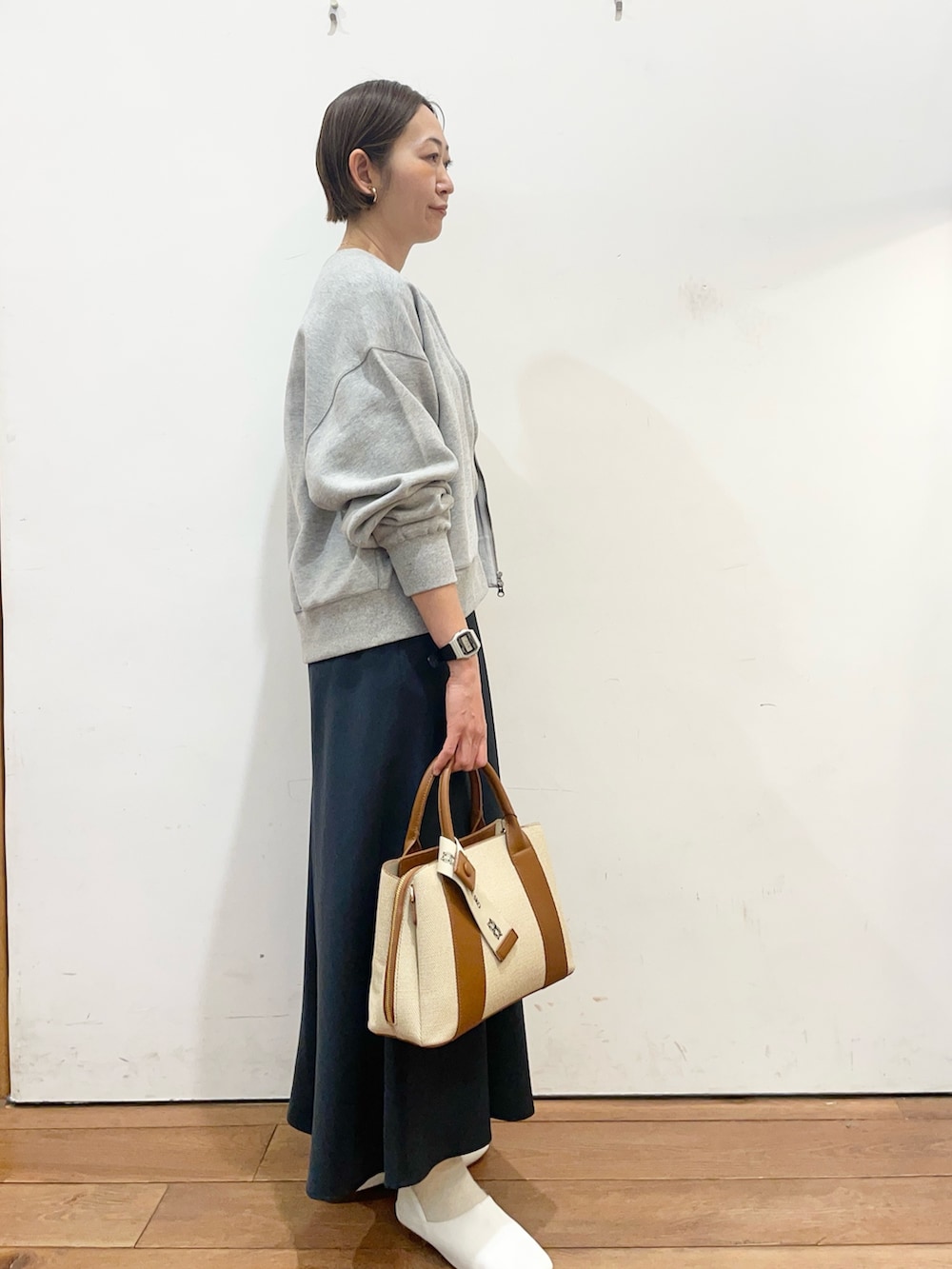 ブルー系のスカート、ホワイト系のその他シューズ、ホワイト系のハンドバッグを着用したレディースの春コーディネートの3枚目の写真