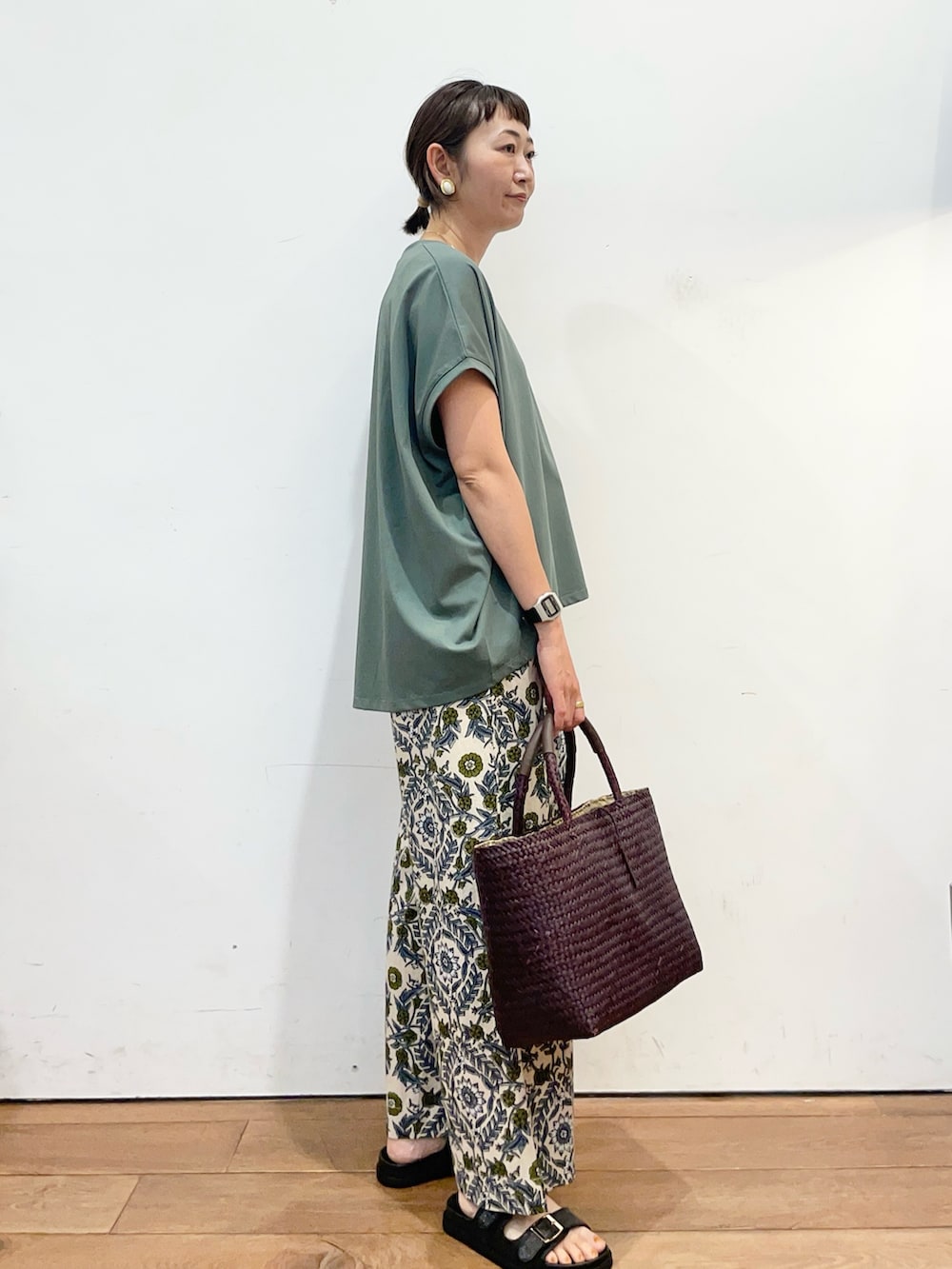 グリーン系のTシャツ/カットソー、ベージュ系のその他パンツ、ブラック系のサンダルを着用したレディースの夏コーディネートの3枚目の写真