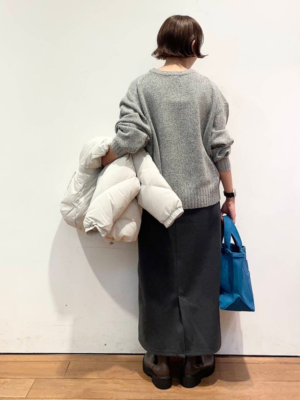 ホワイト系のダウンジャケット/コート、グレー系のニット/セーター、ブラウン系のブーツを着用したレディースの冬コーディネートの7枚目の写真