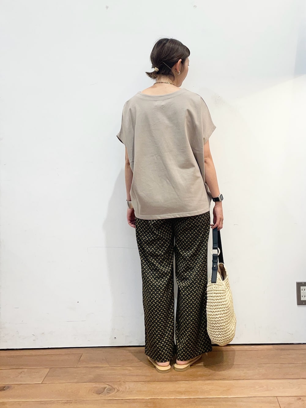 ベージュ系のトートバッグ、ホワイト系のサンダル、グレー系のTシャツ/カットソーを着用したレディースの夏コーディネートの4枚目の写真