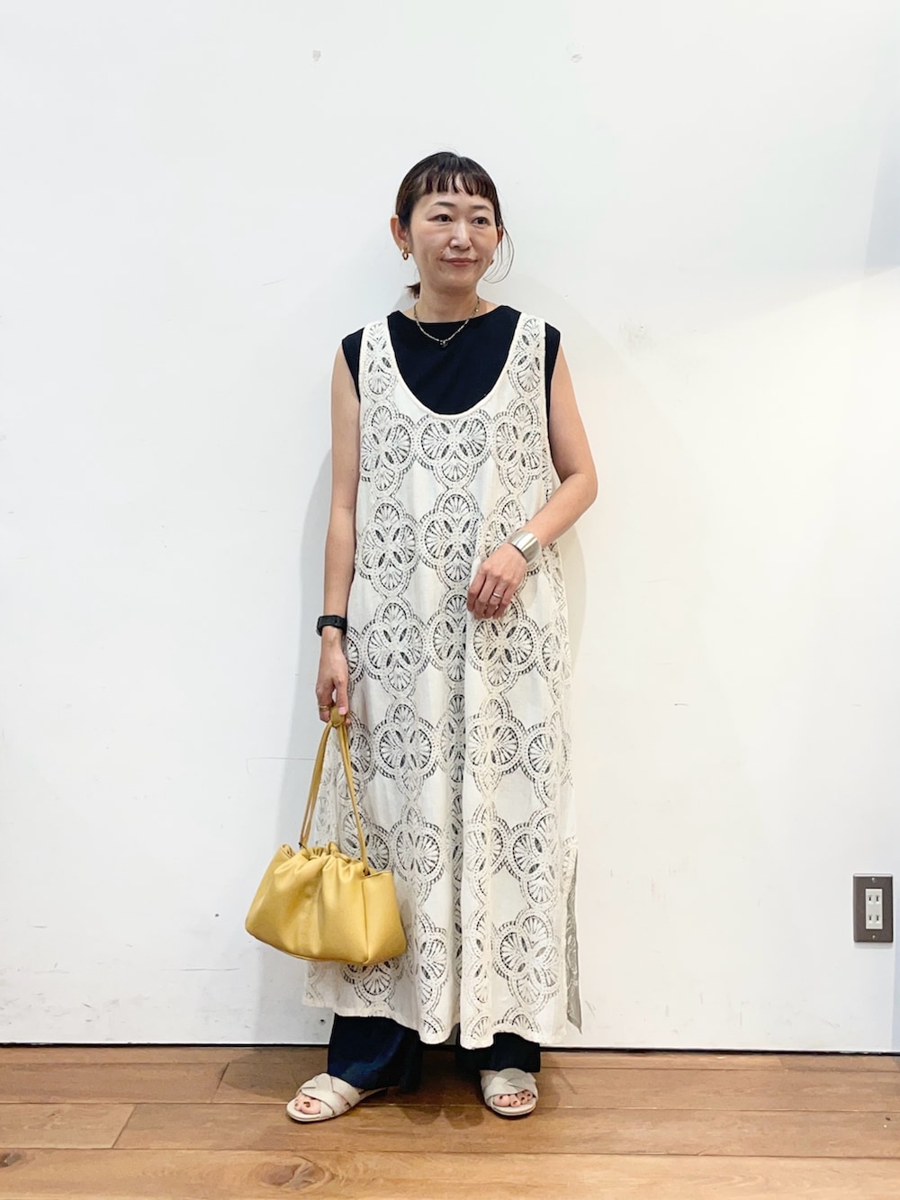 ベージュ系のワンピース、ブラック系のタンクトップ、ベージュ系のサンダルを着用したレディースの夏コーディネートの3枚目の写真