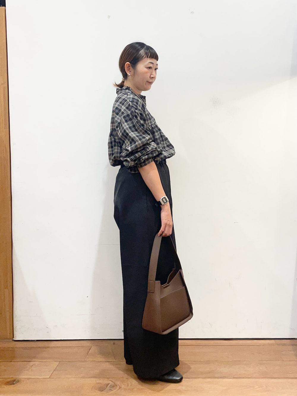 ブラック系のシャツ/ブラウス、ブラック系のその他パンツ、ブラウン系のハンドバッグを着用したレディースの秋コーディネートの4枚目の写真