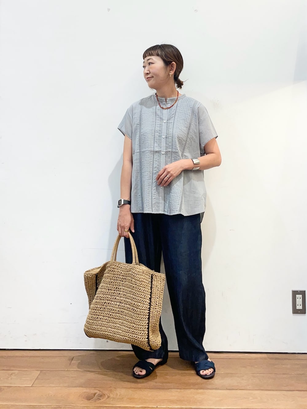 グレー系のシャツ/ブラウス、ブルー系のデニムパンツ、ベージュ系のトートバッグを着用したレディースの夏コーディネートの3枚目の写真