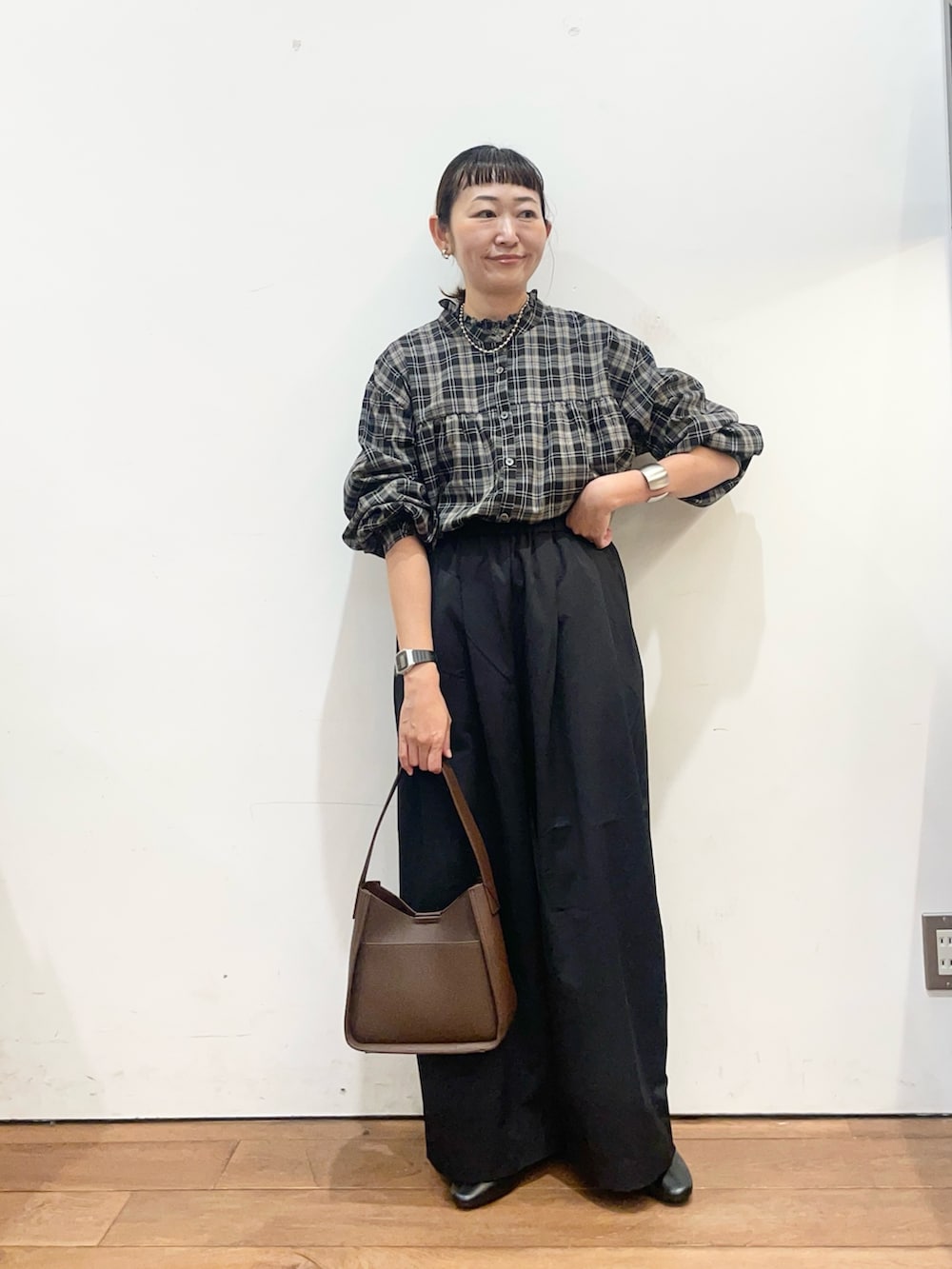 ブラック系のシャツ/ブラウス、ブラック系のその他パンツ、ブラウン系のハンドバッグを着用したレディースの秋コーディネートの3枚目の写真