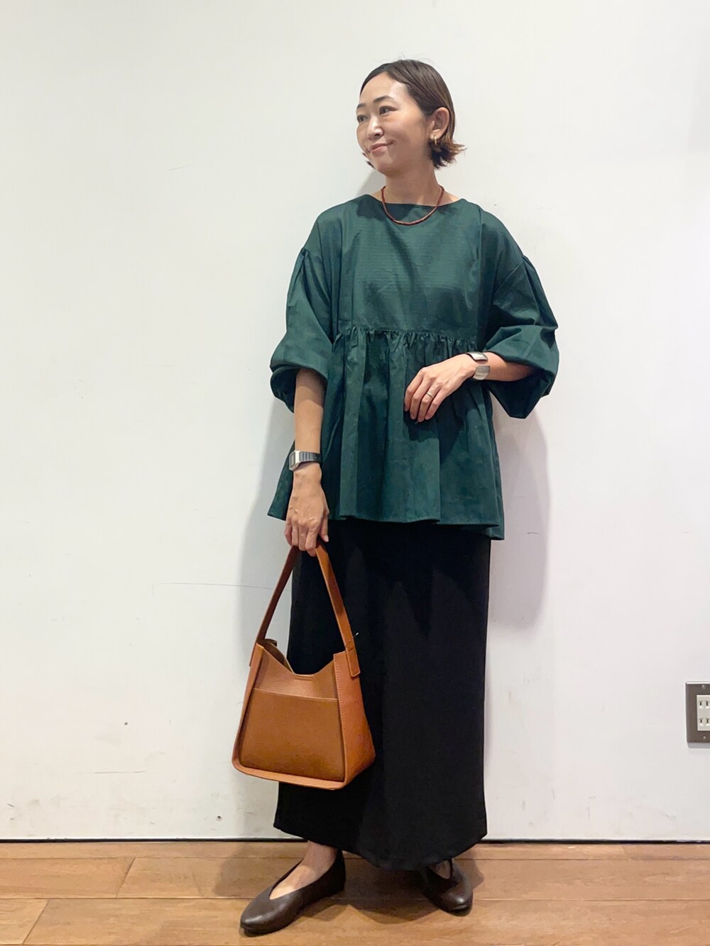 ブラウン系のパンプス、ブラウン系のハンドバッグ、グリーン系のシャツ/ブラウスを着用したレディースの秋コーディネートの3枚目の写真